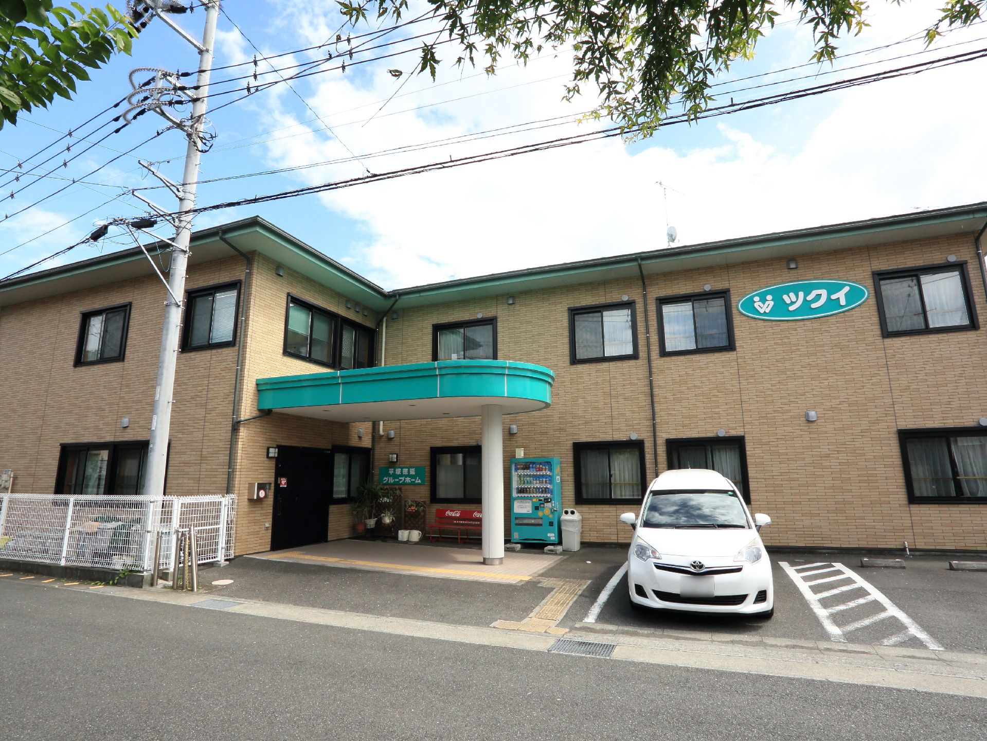 施設の建物は2階建てで、アパートのような造りになっている。外壁はレンガ造り風で、入口付近には自動販売機が置かれている。