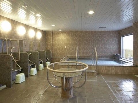 随所に雰囲気を壊すことなく手すりが設置された大浴場。大きな湯船の横には窓があり、竹垣に囲まれたスペースが見える。