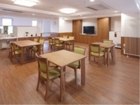 白い壁に木の腰板が張られている。テレビの置かれている壁面は収納になっている。壁には時計が掛かっており、その下には手すりがある。