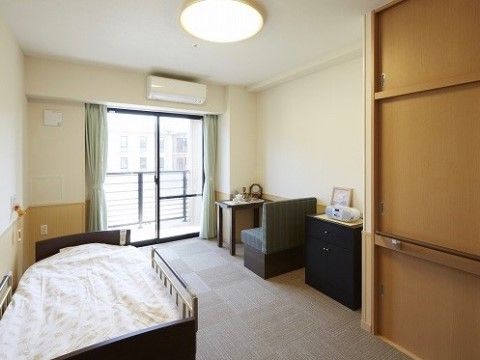 グレーの四角模様のフローリングを取り入れた居室は、落ち着いた雰囲気である。家具などの愛用品を持ち込める十分なスペースを設けている。