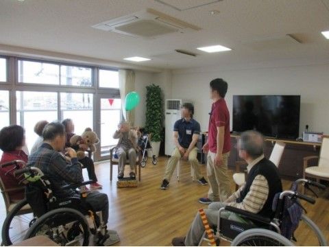 円になって座り風船をつかったレクリエーションを楽しむ高齢者