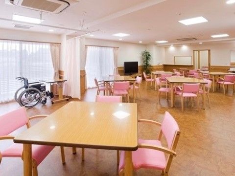 広々としたダイニング。木製のダイニングセットがいくつも置かれている。椅子の背もたれが淡いピンク色で、部屋全体が明るい雰囲気になっている。