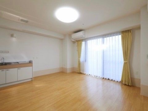 広々とした居室にキッチンが備え付けられている。ベランダもついており、窓からは日の光がたっぷりと入ってくる。