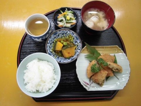 黒い円形のおぼんに盛りつけられた魚の揚げ物がメインの食事