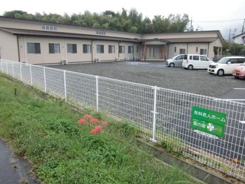 折れ曲がった角の部分に、三角の屋根を持つ入口がある。玄関前には広々とスペースがあり、駐車場を用意している。