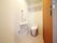 こちらのトイレは、自立できている利用者のトイレ。簡単な手すりと緊急通報装置が付いている。扉は引き戸になっている。