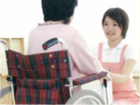 赤いチェック柄の車椅子に乗った入居者様に声を掛けるスタッフ