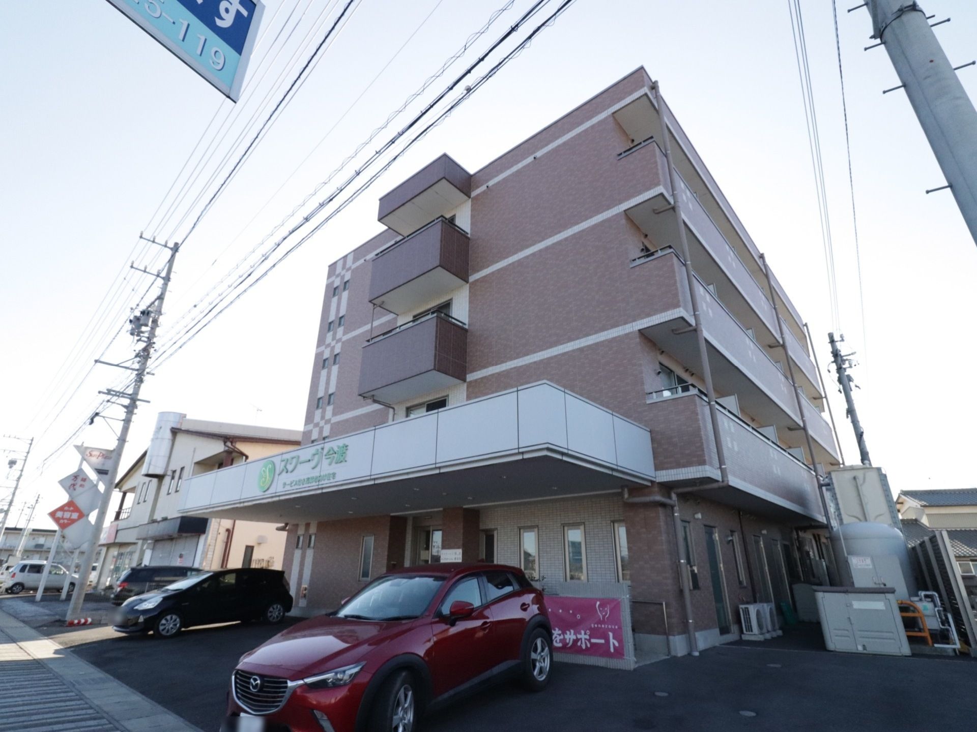 周囲の住宅街にしっくりと溶け込んでいる４階建ての施設の様子。各居室にベランダが設けられているのが見られる。