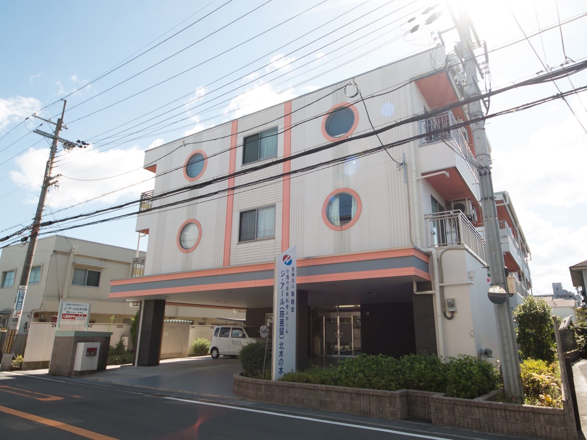 丸い窓が印象的な３階建ての施設である。道路に面した場所に建ち、迷う心配がない。入口に縦長の看板がある。