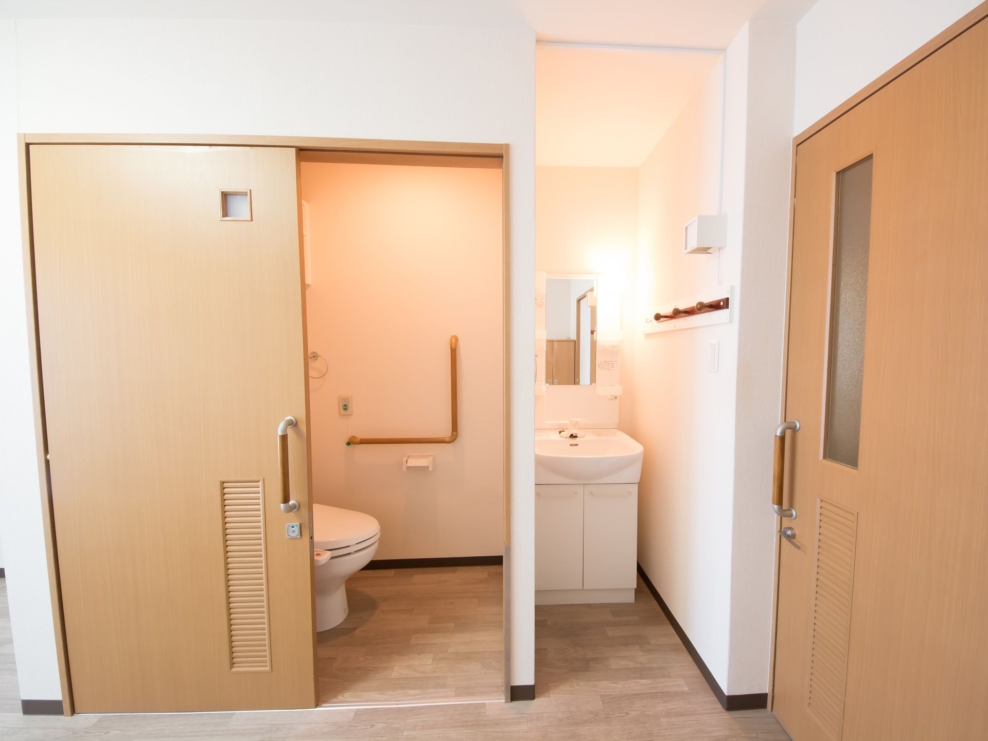 居室の扉を開けると、すぐに洗面台がある。隣にはトイレが完備されており、引き戸式扉で開け閉めが楽に行える。