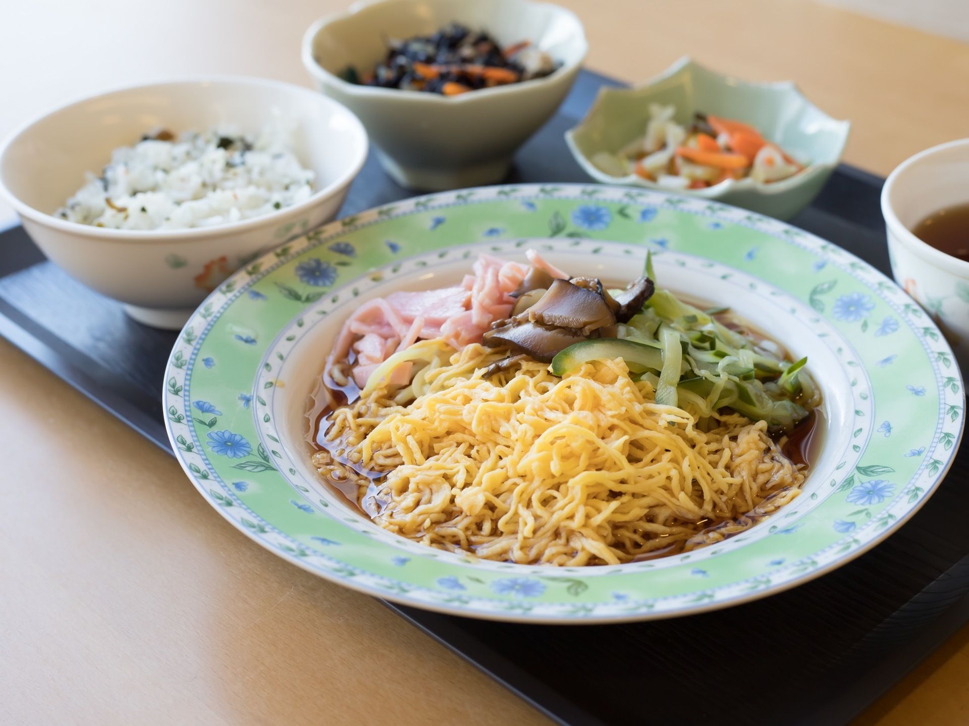 冷やし中華がメインの食事である。ひじきなどの副菜もあり、栄養バランスが考えられている。彩りも豊かな食事内容になっている。