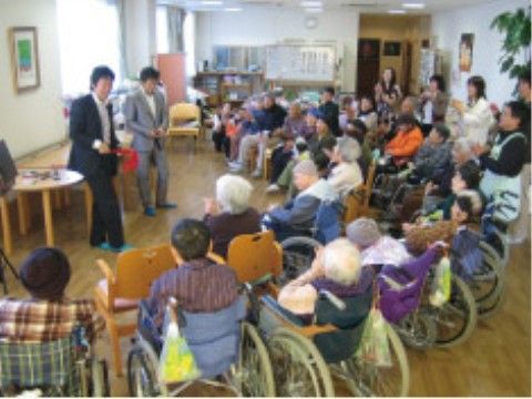 ２人のスーツ姿のスタッフの方を見ている入居者様と他のスタッフ