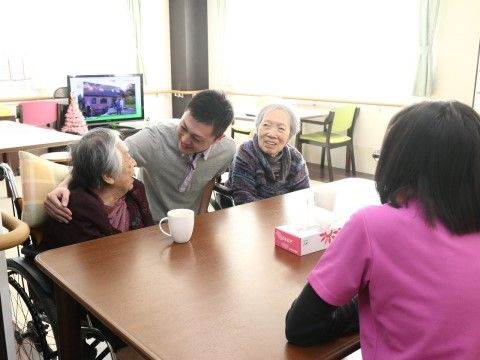 車椅子に乗ったままでテーブルでお茶を楽しんでいる入居者様