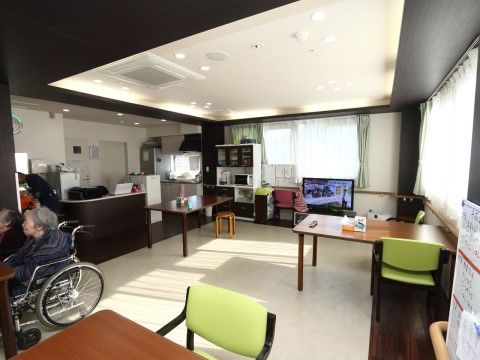 広い空間のリビングには、茶色のテーブルと黄緑色の椅子があり、モダンで温かみのある雰囲気となっている。