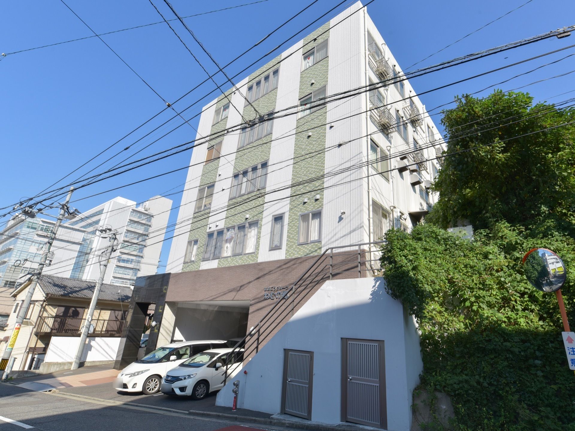 一階部分が駐車場となっており、その上に４階分の住居等スペースがある。白い壁に、薄いグリーンのレンガで模様の入った外観である。