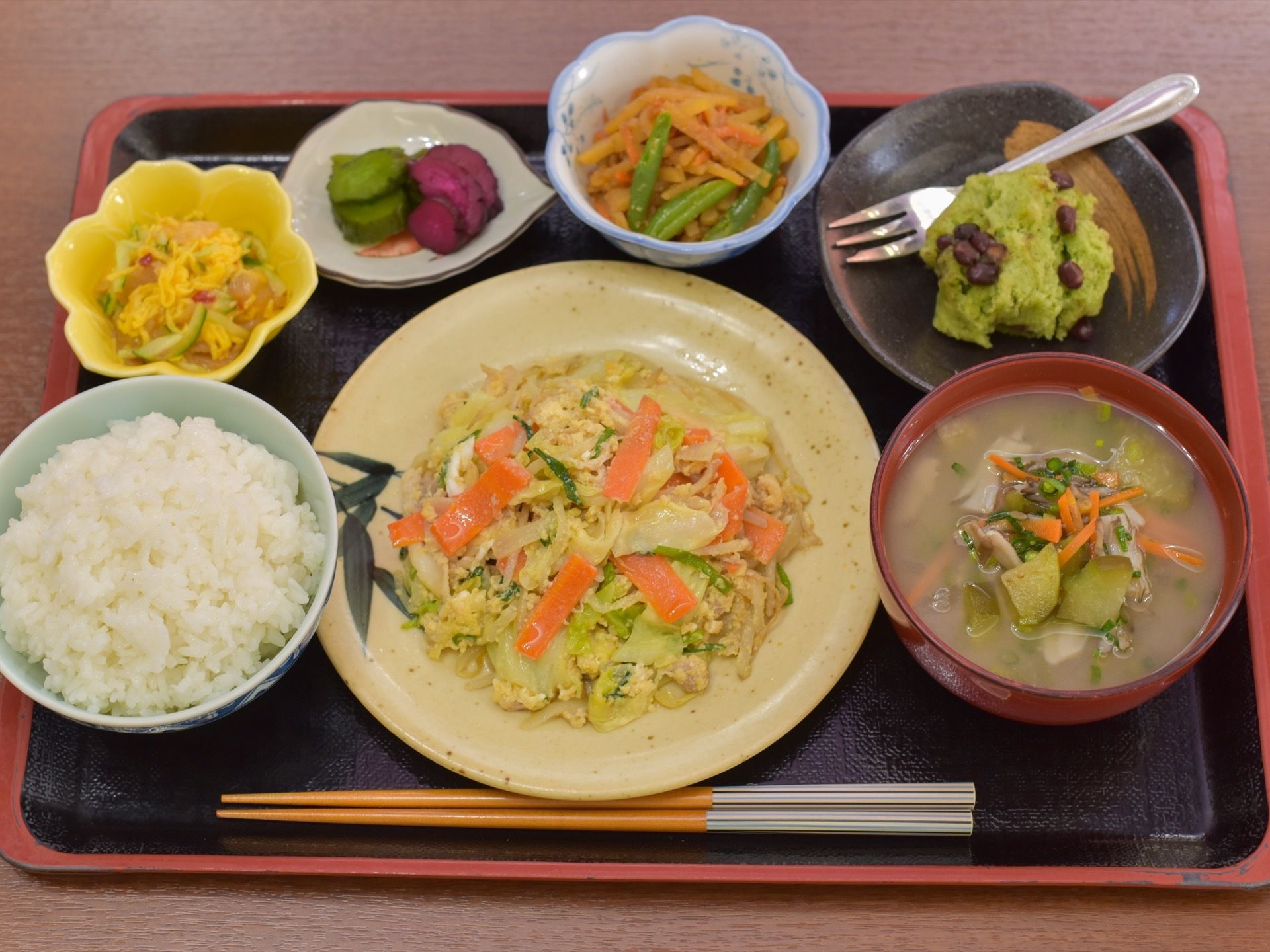 黒トレーに食事が載っている。ご飯、汁物、主菜のほか、漬物を含めて小鉢が３つ、デザートのメニューである。