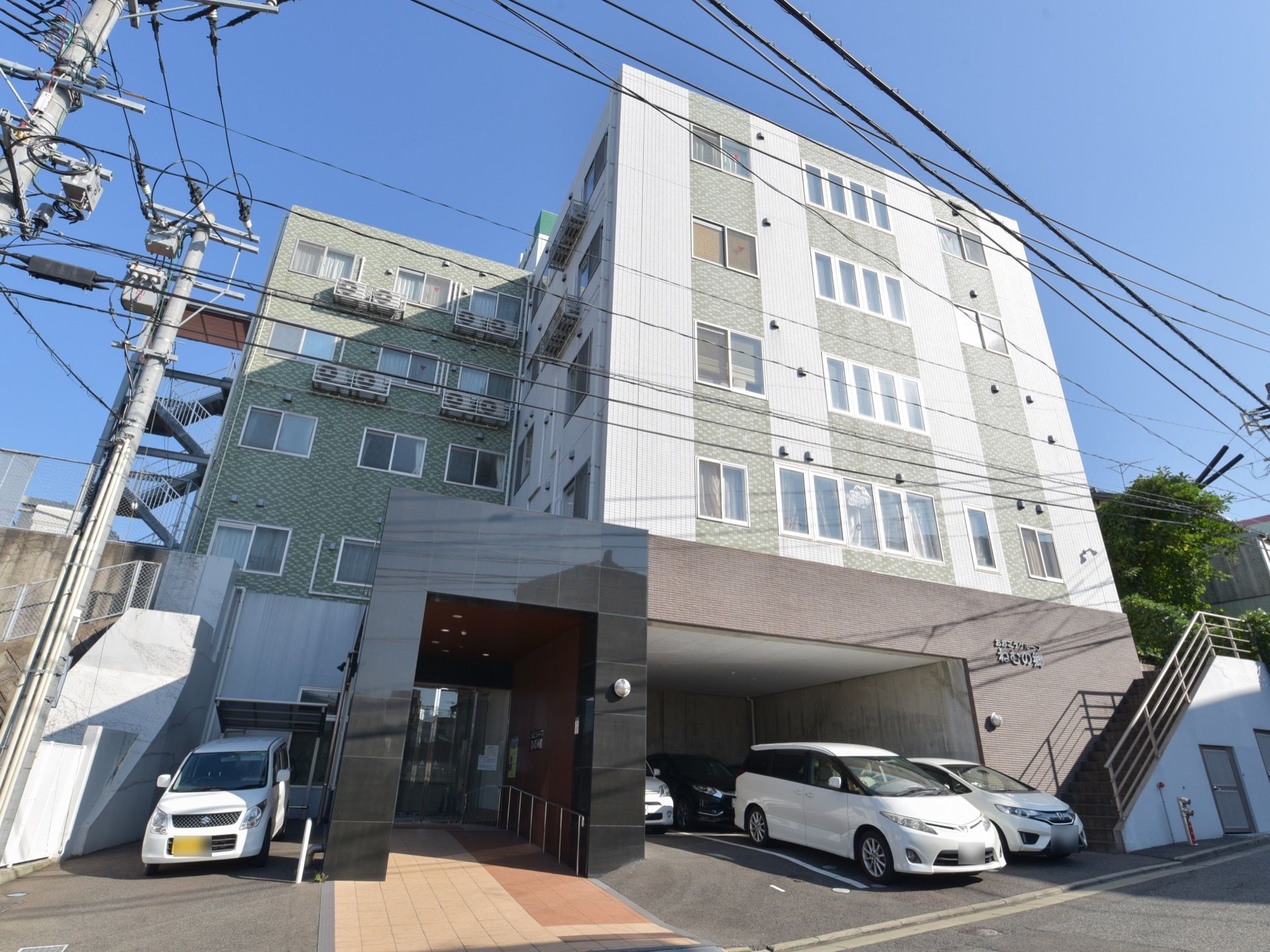 玄関の右側の駐車場の上に施設名が明記されている。その横には２階に上がる外階段がある。非常階段が奥に設置してある。