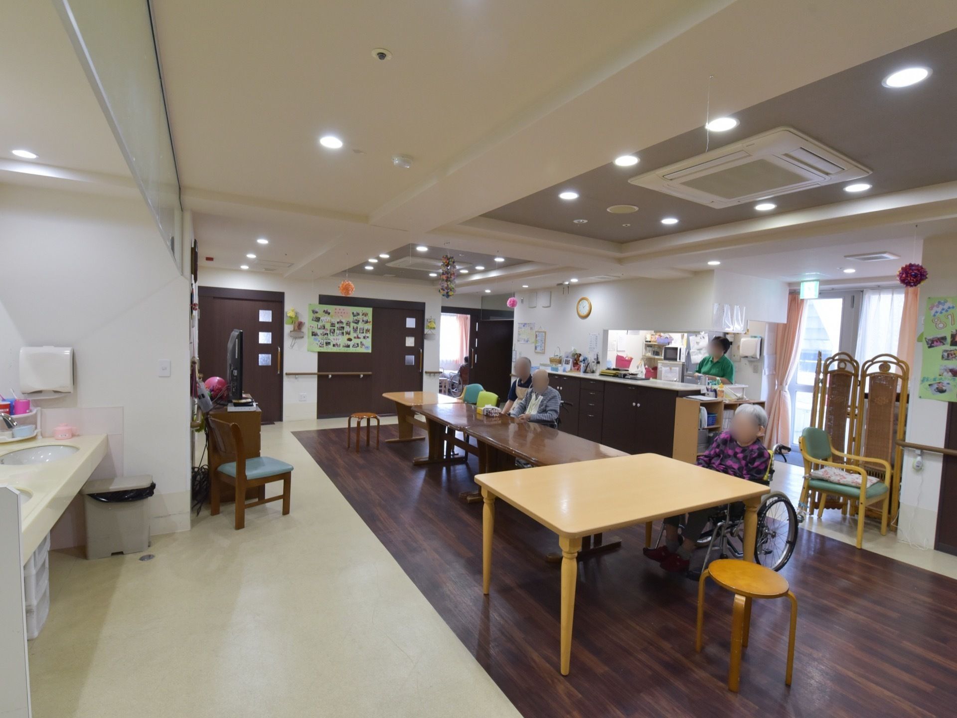 奥にカウンターキッチンがあり、入居者様が配膳を待っているダイニング