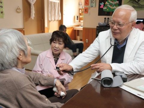 回診に来た医者に聴診器で診察を受けている女性の入居者様