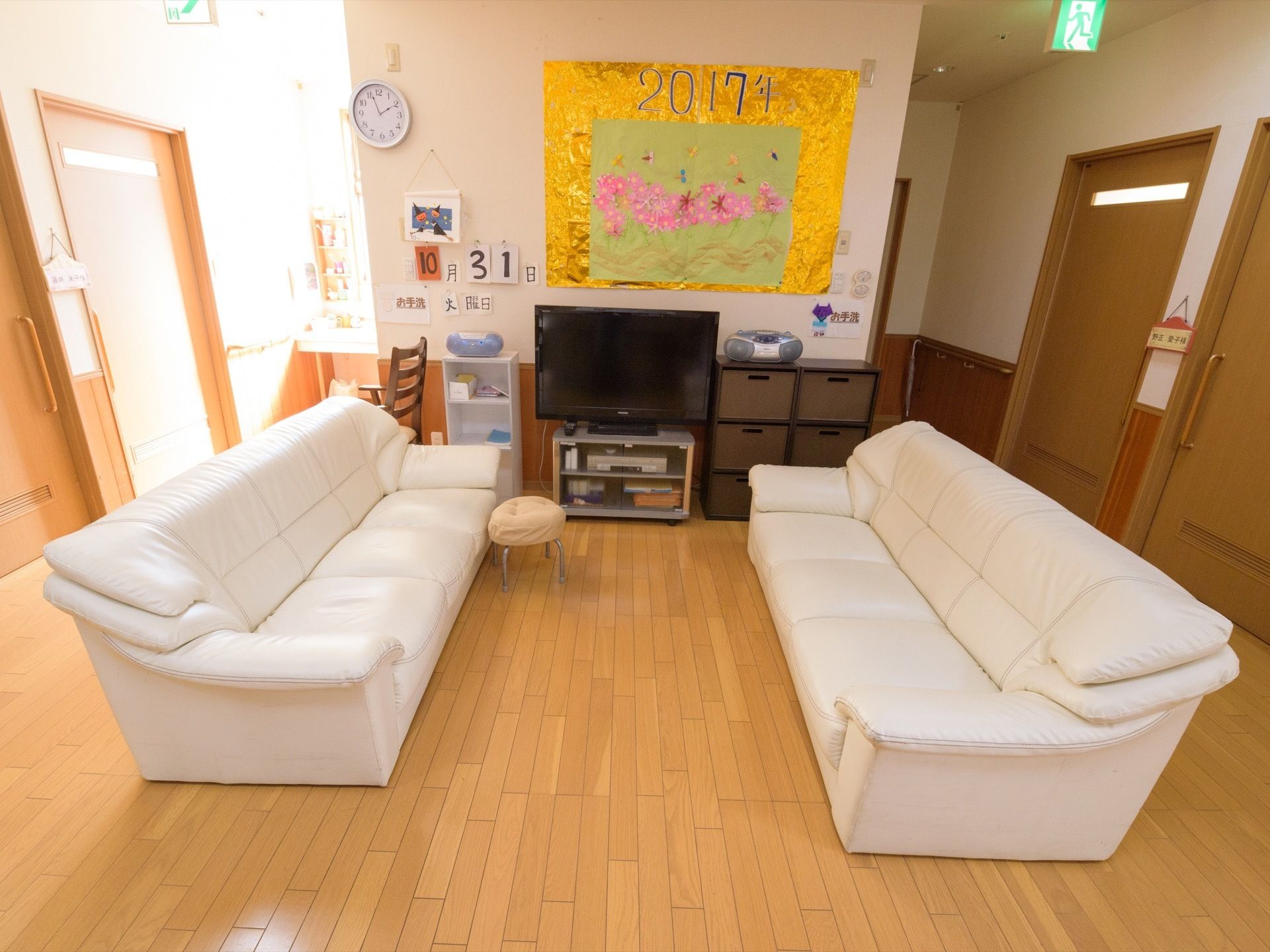 共有スペースの壁際には、さまざまなレイアウトに工夫を凝らしている。壁の中央前にテレビを置き、白色の壁には、丸時計を掛けている。