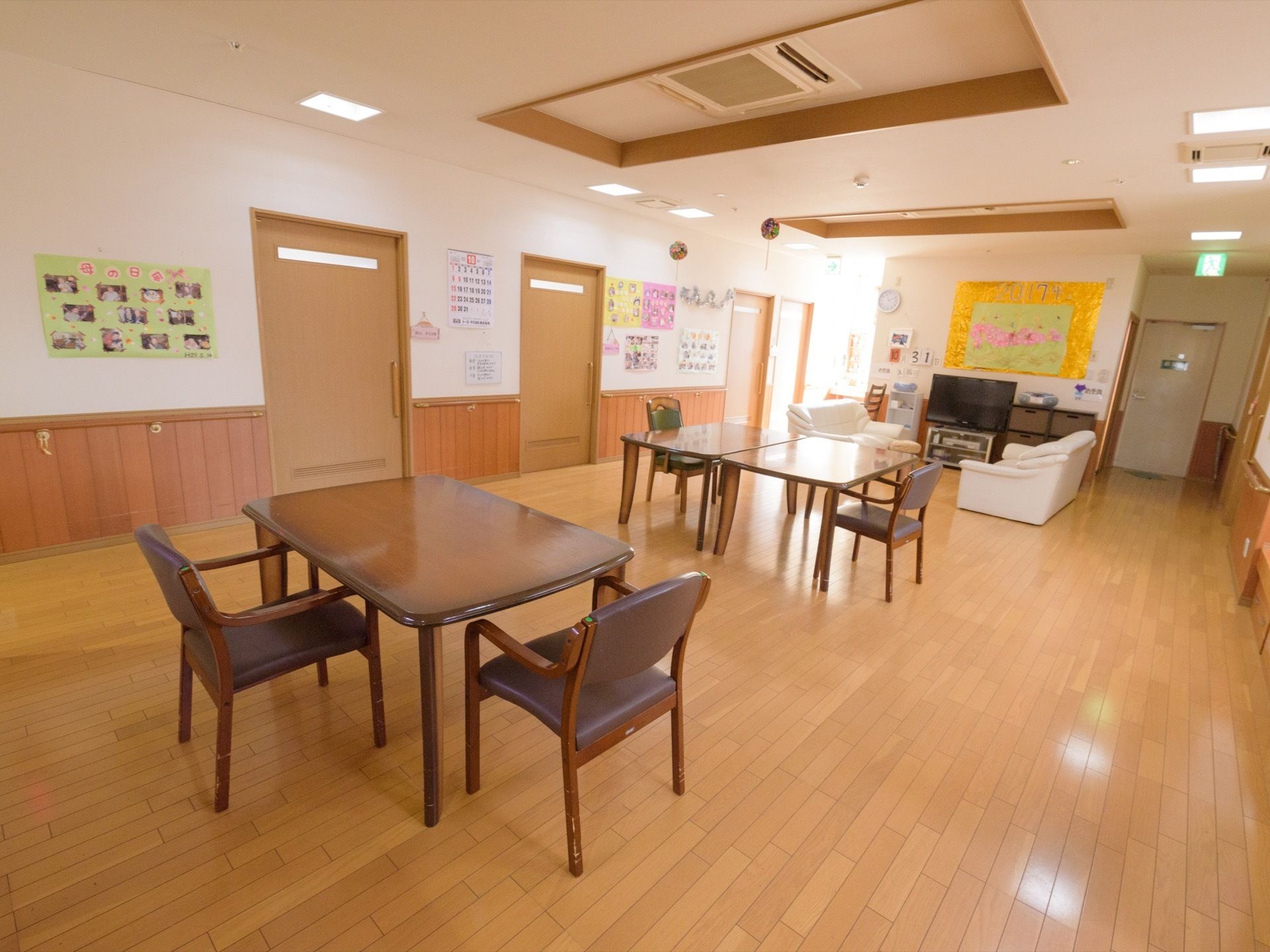 天井には、窪みの部分を設け、エアコンを設置している。焦げ茶色のテーブルと椅子を並べて置いている。壁際には手すりを取り付けている。