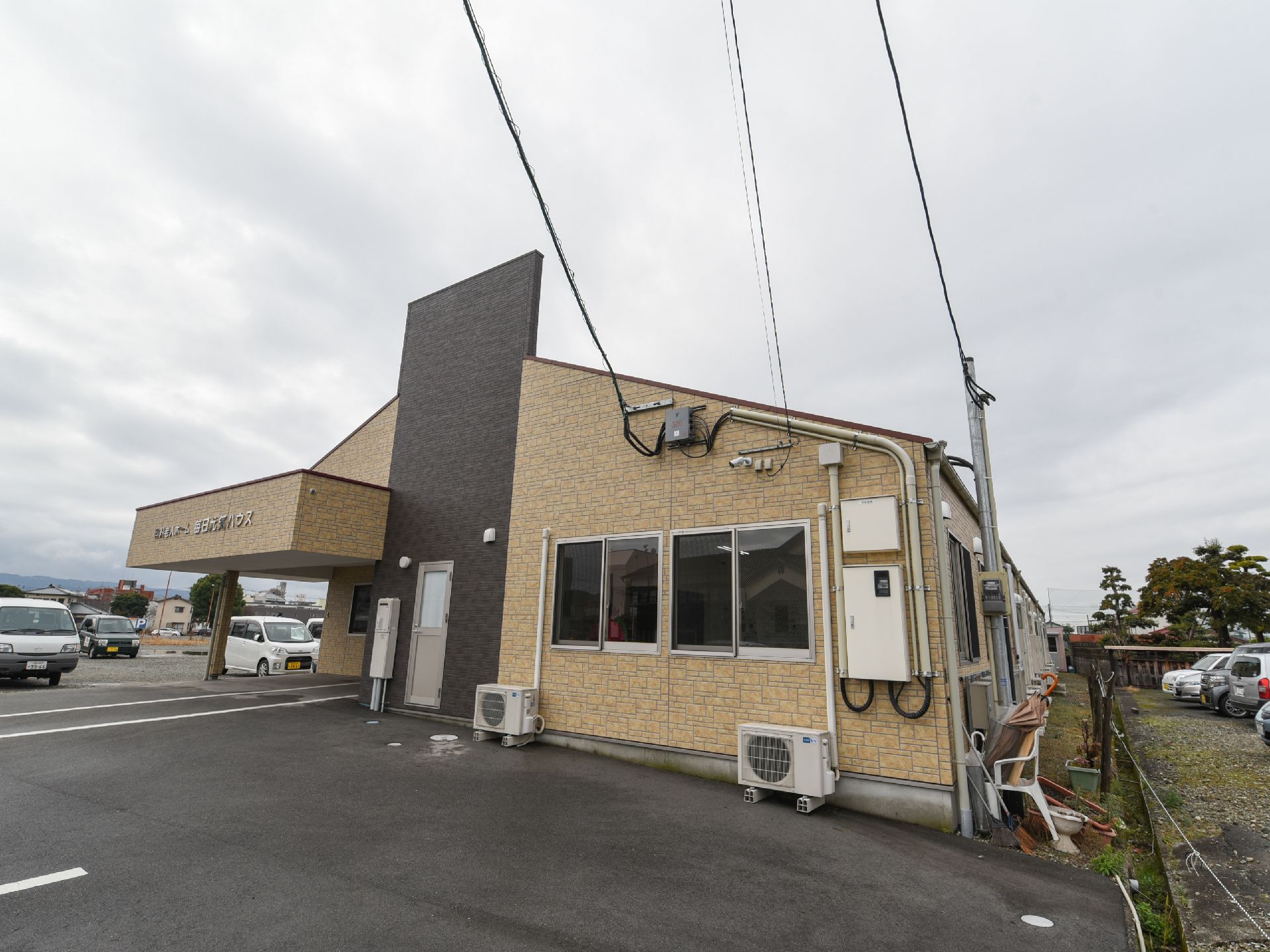 黄色いレンガが貼られた１階のみの建物で、奥へ長く続いている。黒い壁が中央部に立っている。施設の外に室外機が置かれている。