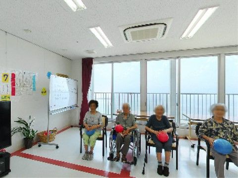 椅子に座ってボールを使ったレクリエーションを行う高齢者