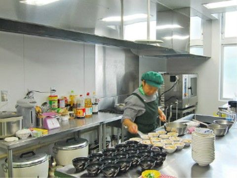 厨房で器に料理を盛り付けるスタッフ