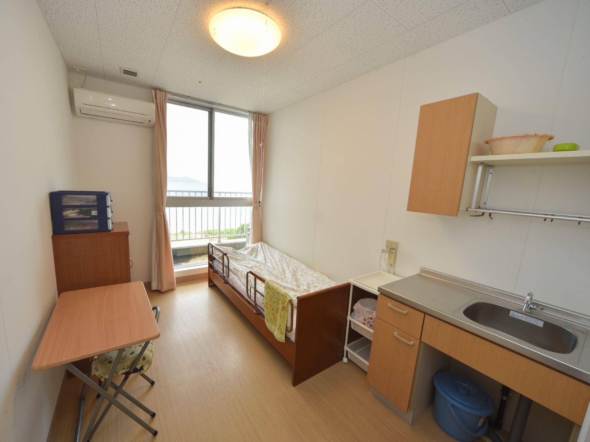 細長い形となっている個室には様々な家具があり、洗面台やテーブル、収納ボックスなどがある。窓の外は豊かな自然風景となっている。