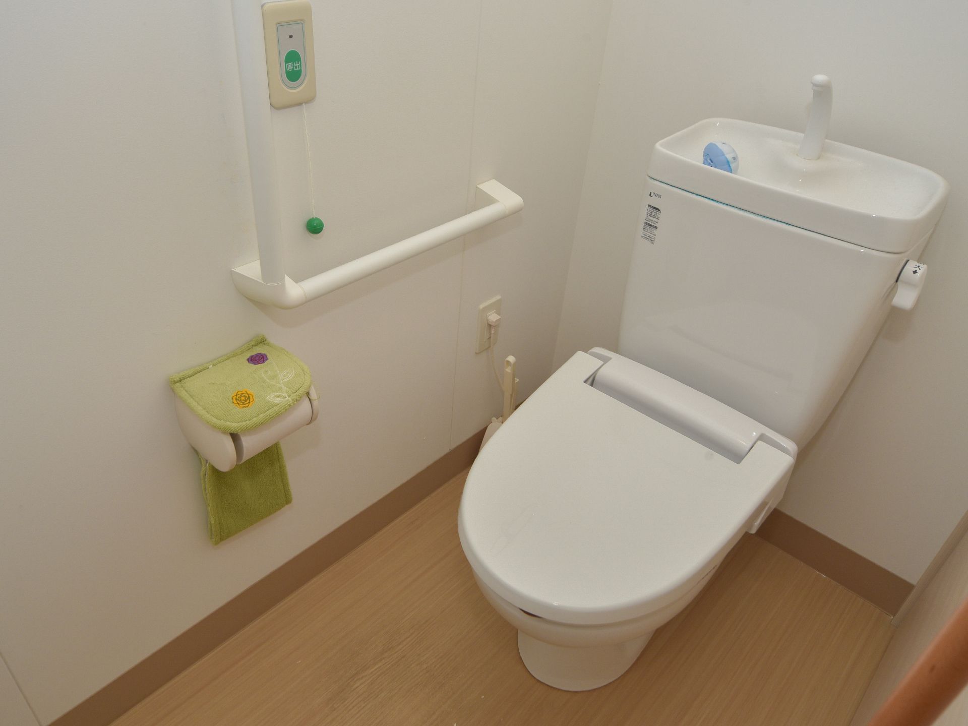 トイレルームにある便座の壁際にはL字型の手すりとカバー付きのトイレットペーパー、そしてスタッフ呼び出し用ブザーが設置されている。