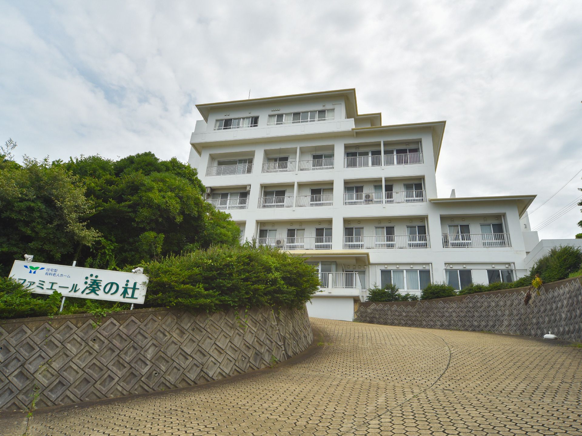施設を外から見た形となっており、施設名の書かれた看板、木々が手前にある中、5階建ての建物となっている。