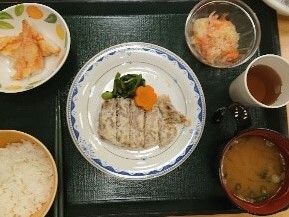 ステーキに天ぷらや酢の物、味噌汁がついた定食のトレイ