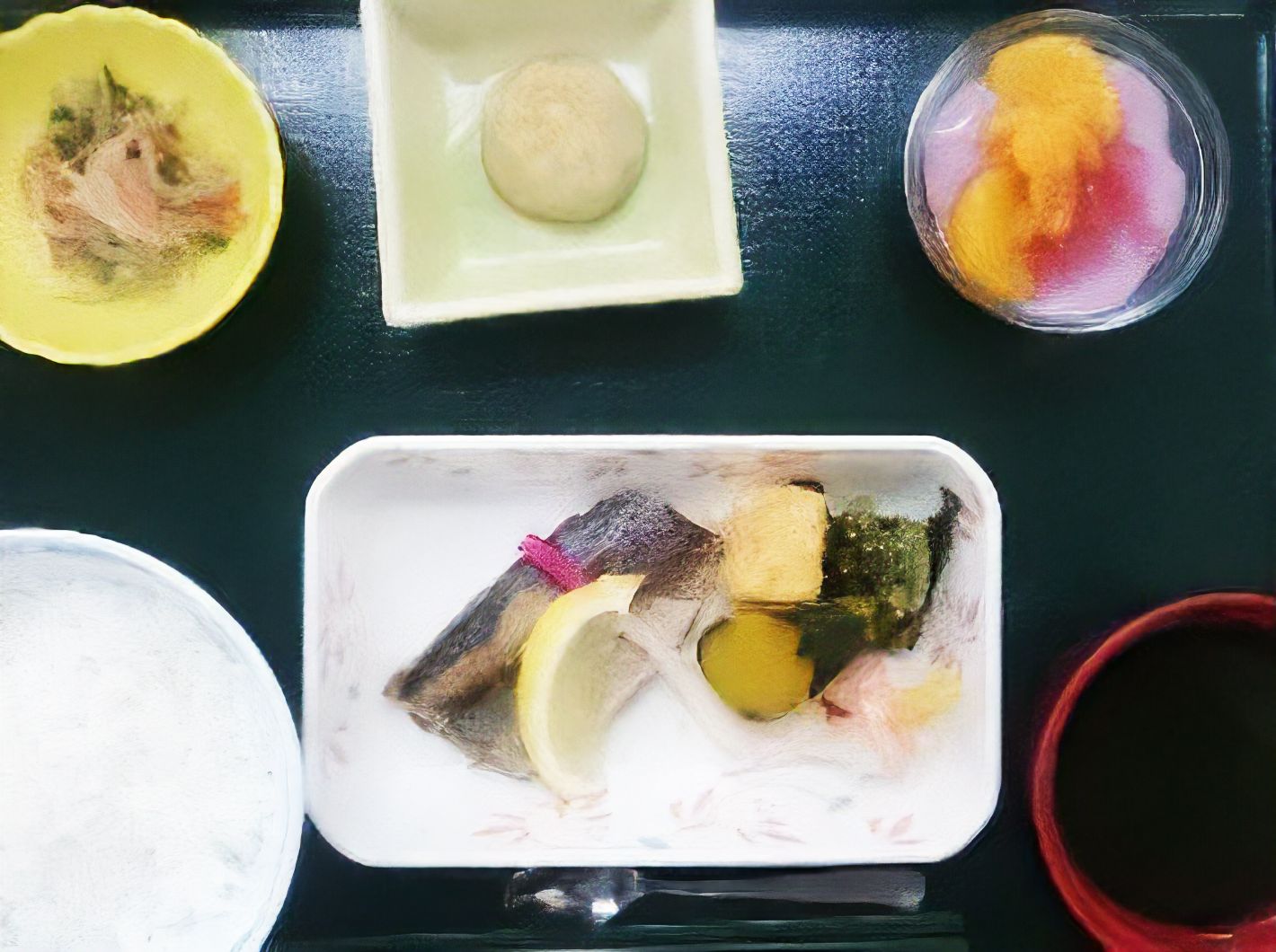 5品ほどの料理と白米が載った茶碗。それらが黒いお盆に乗ってる