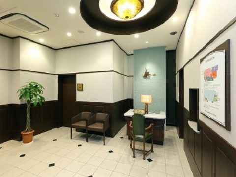 エントランスにはテーブルと種類の異なる椅子が用意されている。壁には施設の案内図が貼られており、観葉植物が飾られている。