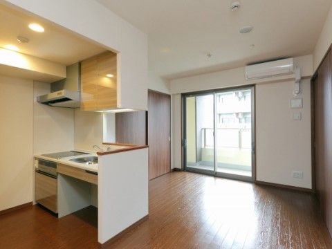 居室は広々としており、対面式キッチンがある。キッチンからは部屋全体が見渡すことができる。エアコンが設置されている。