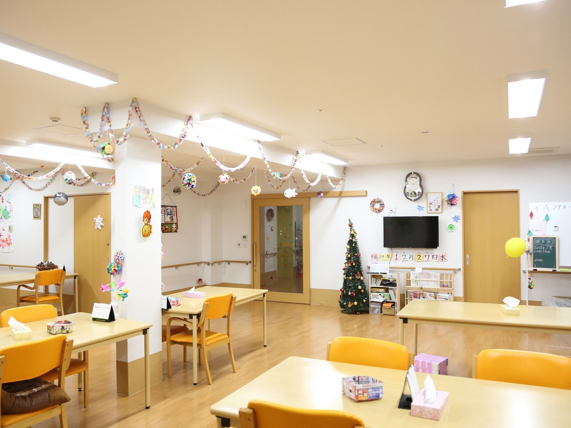正面の壁にはテレビがあり、その下に大きな文字で日付表示がされている。クリスマスは過ぎているが、ツリーが飾ってある。