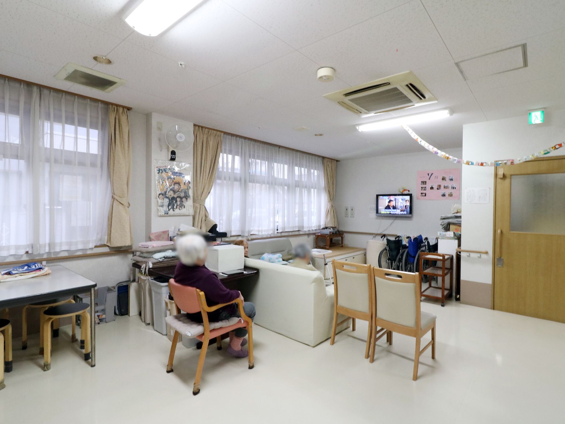 空調があり白で統一された室内にはソファや椅子が置かれ、テレビも設置されている。左側は大きな窓になっている。