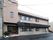 2階建の薄茶色の施設になっている。黒い看板に施設名が入っており左側の入り口は少し奥まっていて道路に面している。