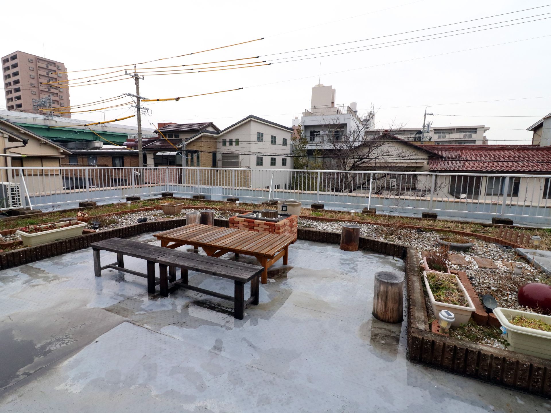 建物の屋上にレンガを並べて作られた花壇と木製のベンチ