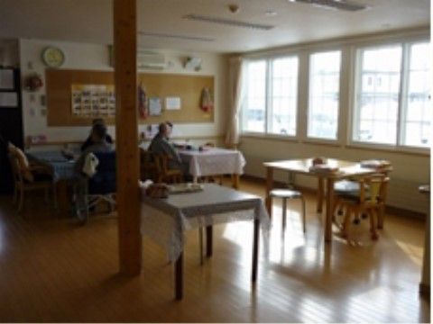 壁に大きなコルクボードがあり、その前でくつろいでいる入居者様