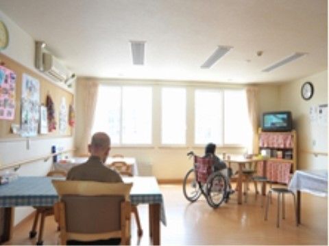 電源が入ったテレビを見ている車椅子に乗った入居者様と男性