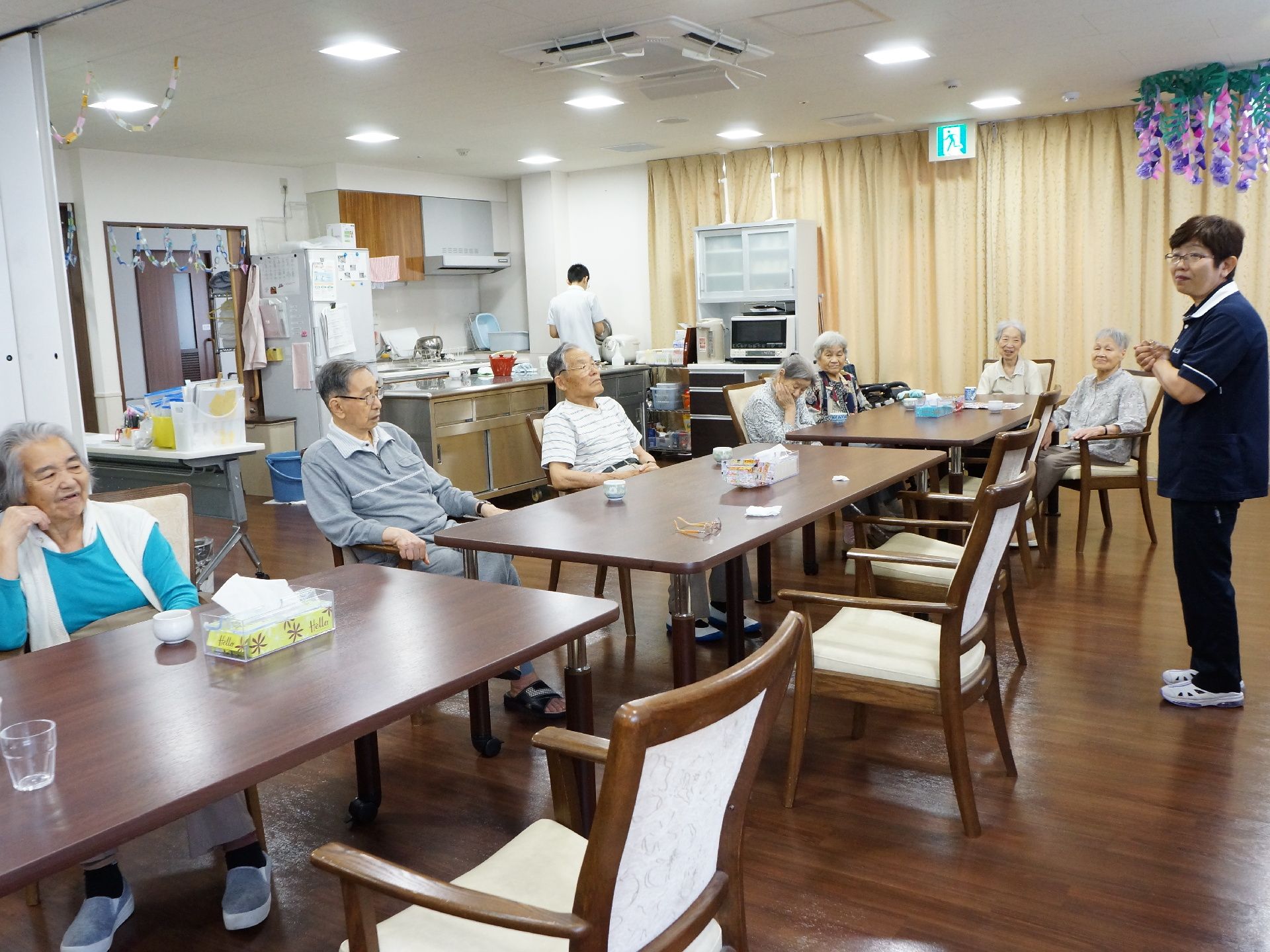 リビング内にキッチンが設置してある。食事の場所としても使われている。テーブルや椅子などは落ち着いた色の家具を採用。