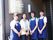 施設長と3人の女性スタッフ。施設長は女性で、服装は私服スタイル、スタッフはポロシャツにパンツスタイルで、青いエプロンをつけている。