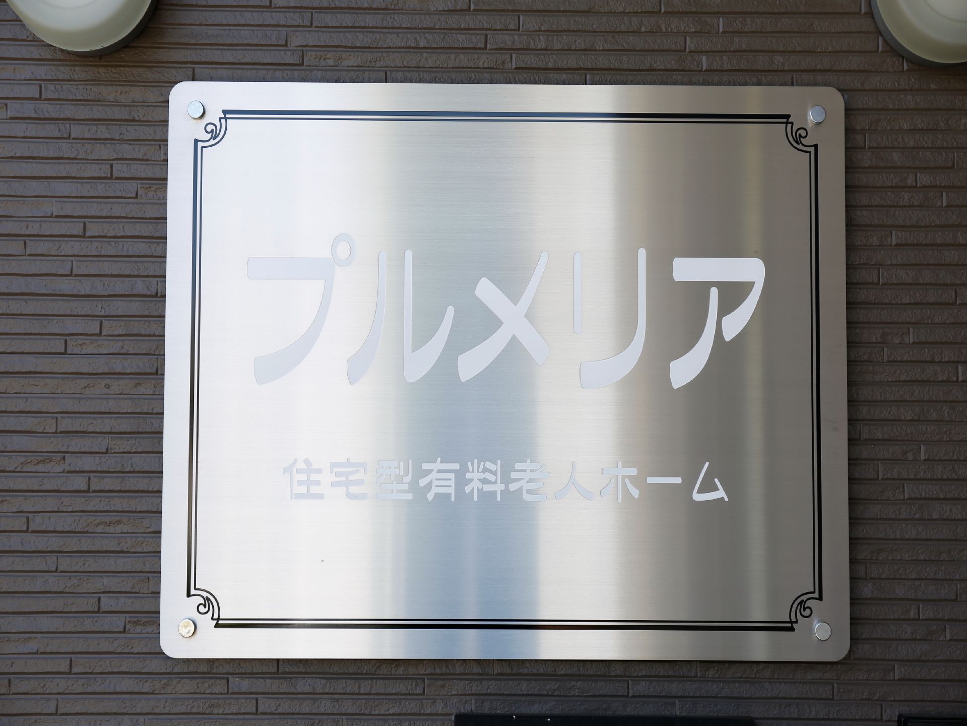 ダークグレーの壁に取り付けられた、白地で施設名が書かれた看板