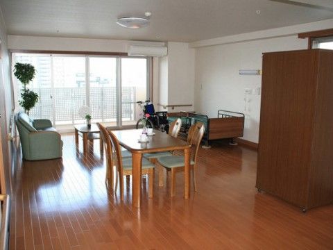 介護ベッドやダイニングテーブル、ソファーなど大きな家具を置いても充分な広さが確保された居室である。窓際に観葉植物が飾られている。
