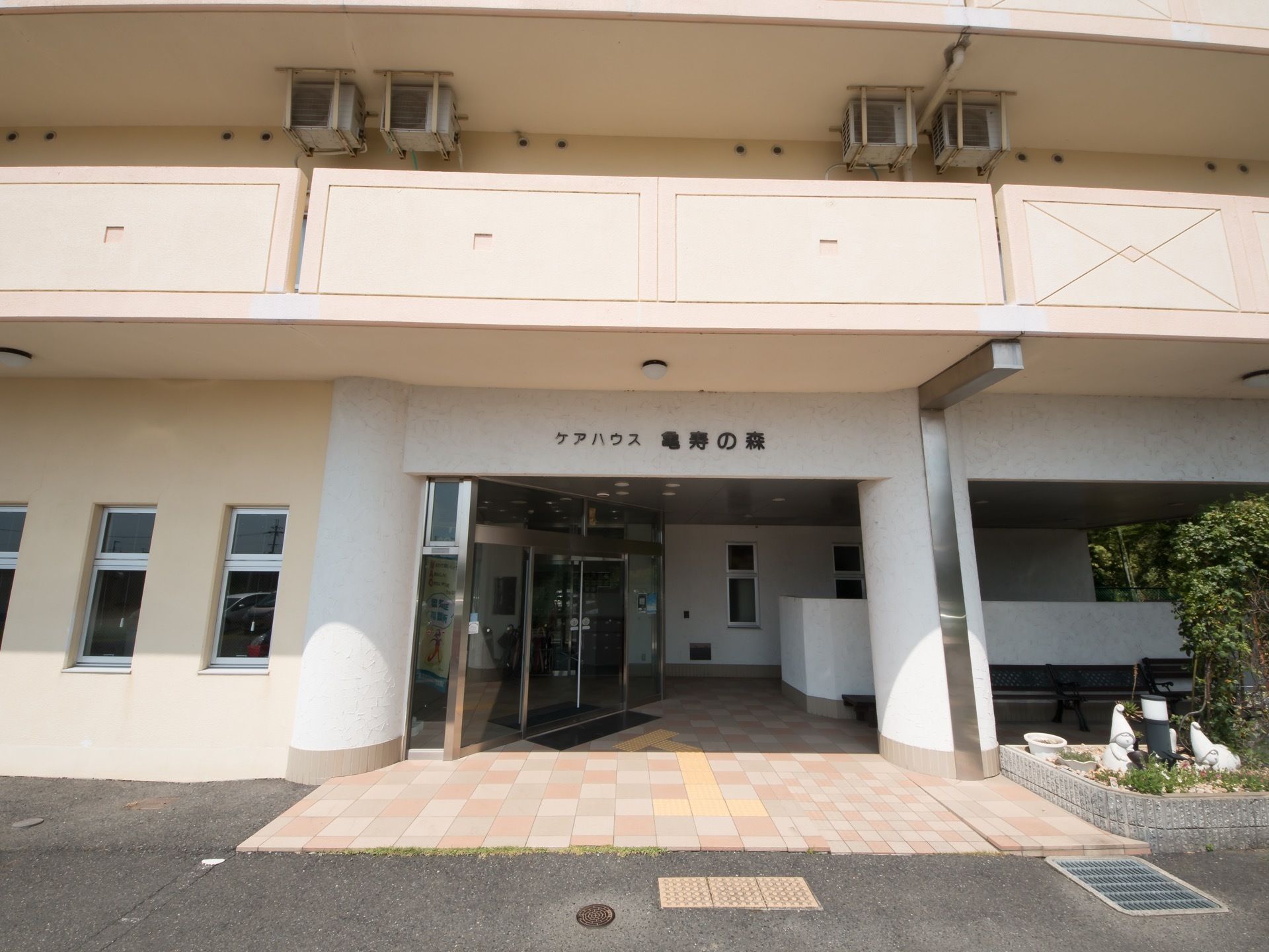 玄関口付近を正面から見た写真。右側にブロックで囲われた植え込みが配置されていて、中にはライトポールが立っている。