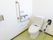 温水洗浄便座付きトイレである。右手の壁にＬ字型の手すりとナースコール、トイレの操作盤が取り付けられている。