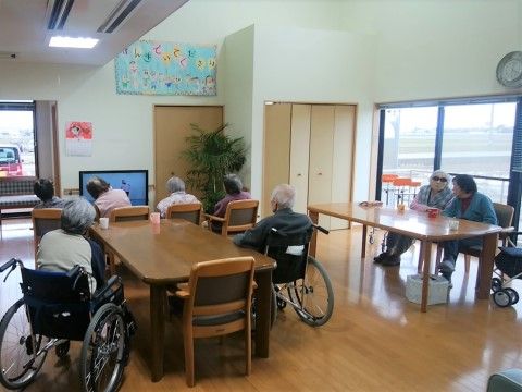 壁の前に置かれた液晶テレビの方を向いて座っている入居者様