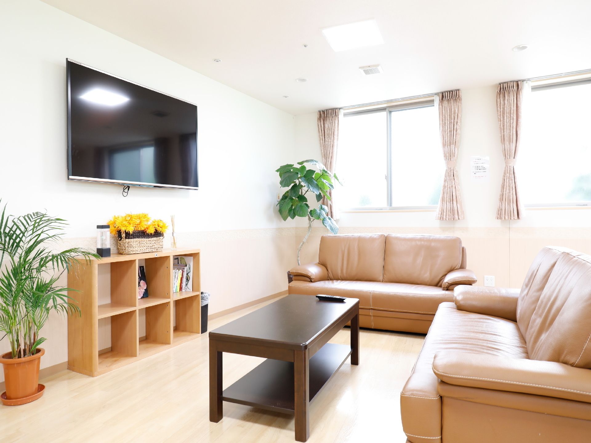 壁に直接取り付けられているテレビの方に向かって置かれたソファセット