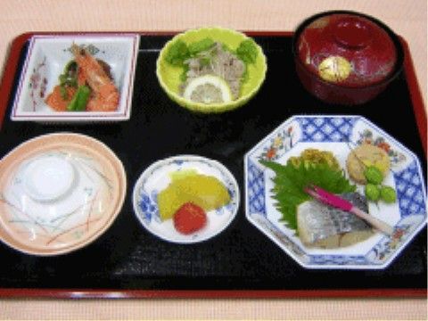 黒いお盆に盛りつけられた、焼き魚や煮物などの和食メインの食事